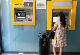 Una mujer sacando dinero de un cajero, en una imagen de archivo.