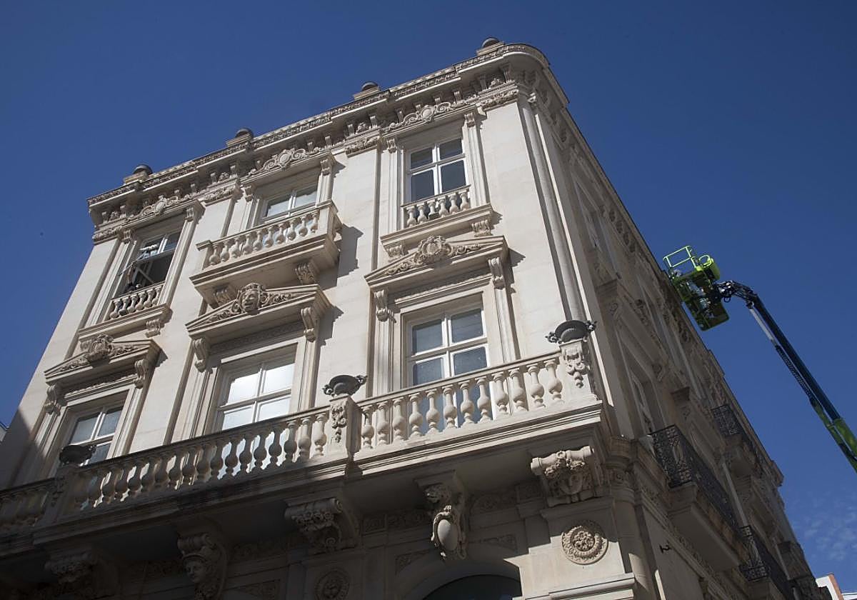 Obreros en una plataforma realizan trabajos en la fachada de la Casa Pedreño.