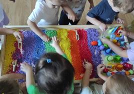 Niños jugando con arena de colores.