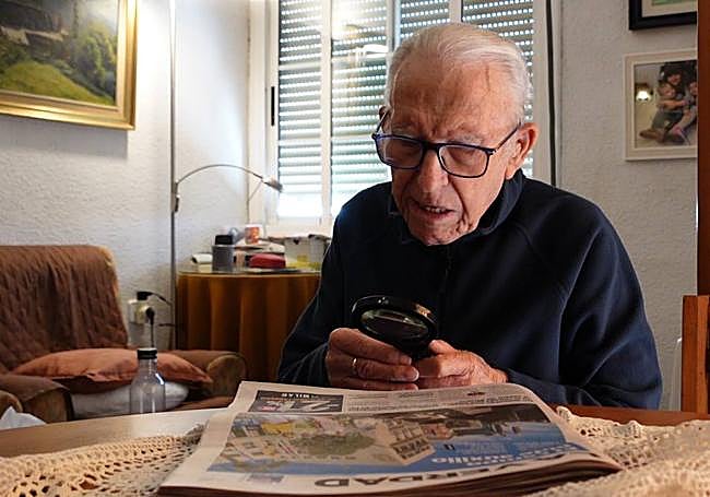 Francisco Martínez leyendo el periódico con una lupa debido a su falta de visión.