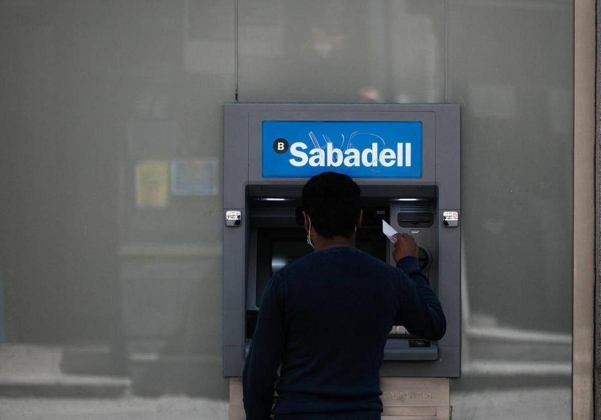 Un hombre sacando dinero en un cajero, en una imagen de archivo.