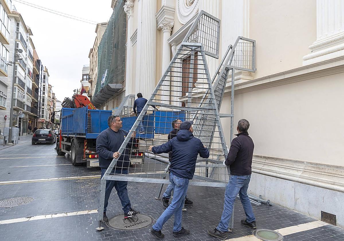 Imagen principal - Empleados municipales colocan en la Caridad las rejillas para formar el manto de flor para la Virgen. Preparativos en el interior de la basílica para los actos de hoy. Los bomberos ponen una malla en la Casa Llagostera, de la calle Mayor.