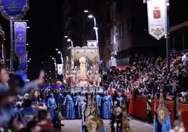 El trono de la Virgen de los Dolores avanza por la carrera mecido por los portapasos, ante el público puesto de pie, en la procesión que presidió el Paso Azul.