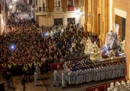 Cientos de personas siguen en la calle del Aire la salida del trono de la Virgen de la Piedad, llevada a hombros por sus portapasos.