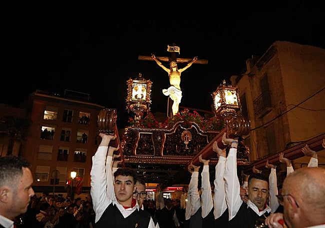 Momento en el que los costaleros del Cristo de la Sangre alzan el trono frente al puente viejo.