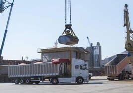Una grúa del puerto echa cereal en una tolva para cargar camiones.