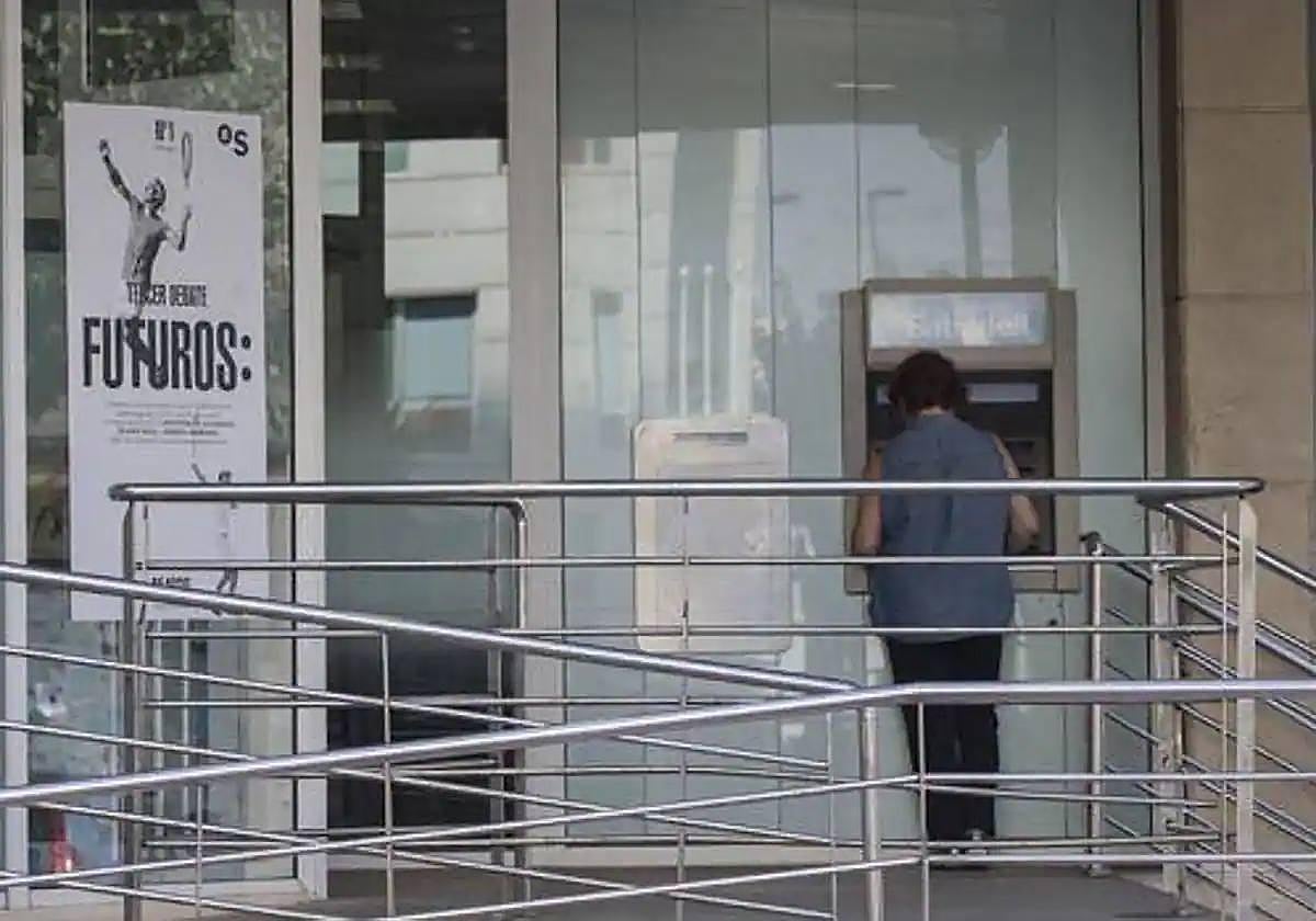 Una persona sacando dinero de un cajero automático, en una imagen de archivo.