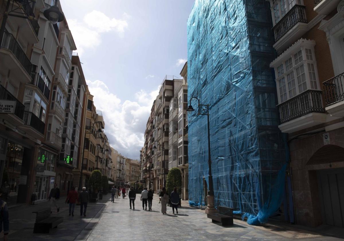 Un edificio de la calle Santa Florentina, con un andamio en su fachada cubierto por una lona, donde una grupo de albañiles realiza arreglos.