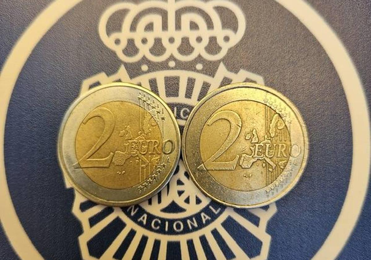 Una moneda real de dos euros y una falsa al lado.