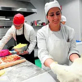 Alumnos de la Escuela de Hostelería de Cáritas preparan unas pizzas para un cáterin.