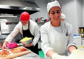 Alumnos de la Escuela de Hostelería de Cáritas preparan unas pizzas para un cáterin.