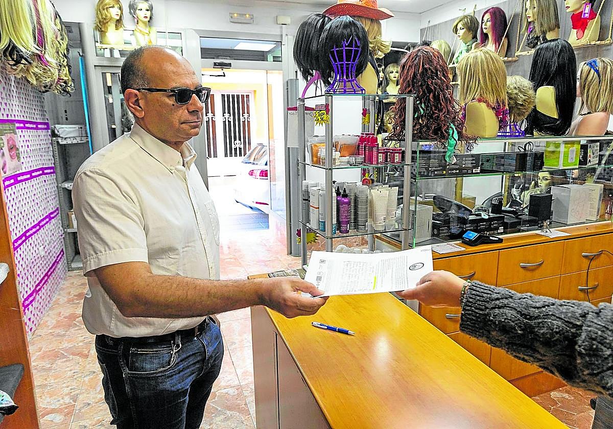 Un vecino entrega su firma para exigir la restitución del servicio entre Cartagena y Madrid en la tienda Comercial Rubio.