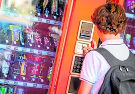 Un chico selecciona una bebida energética en una máquina expendedora.