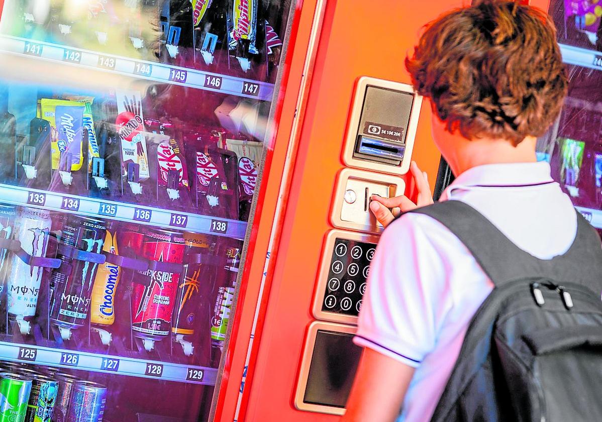 Un chico selecciona una bebida energética en una máquina expendedora.