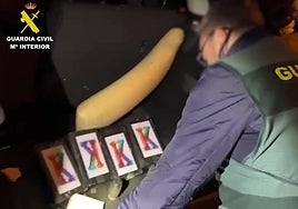 Un agente descubre los paquetes de cocaína ocultos en el doble fondo de un vehículo.