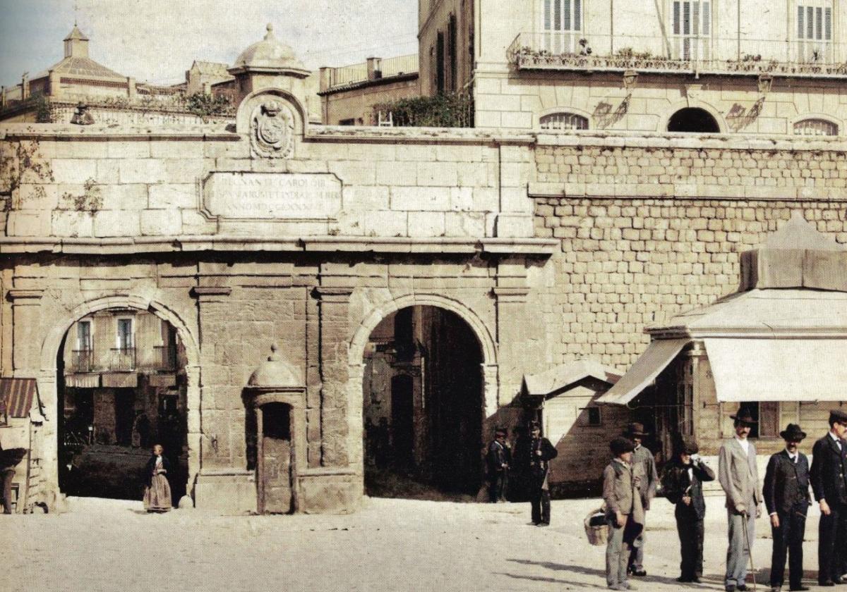 Varios vecinos dialogan frente a la desaparecida Puerta del Muelle, derribada en el año 1900.