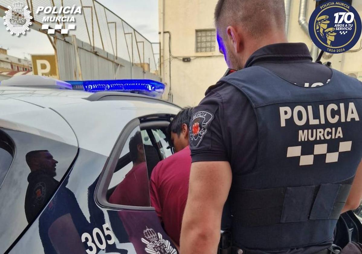 La Policía Local de Murcia meten al detenido en el coche.