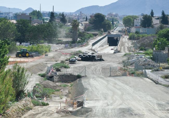 En primer término, vallado con cintas, la zona donde estaba el antiguo paso a nivel, eliminado por Adif; al fondo, salida del túnel a la superficie del AVE.