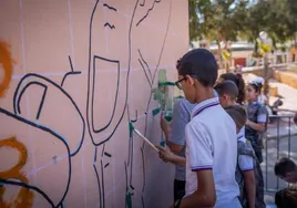Los niños del colegio Jesús-María estrenan los pinceles en uno de los muros del centro.