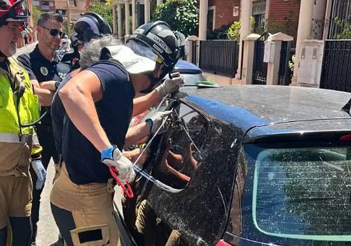 Efectivos de bomberos rescatan a un niño del interior del coche.