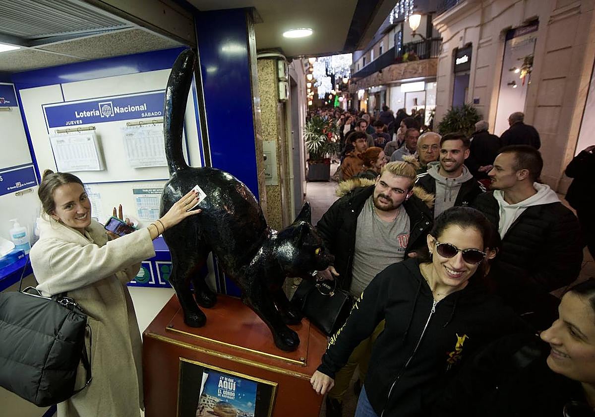 Una gran cantidad de personas se agolpan en la puerta de la administración El Gato Negro en Murcia para adquirir un décimo de la Lotería de Navidad