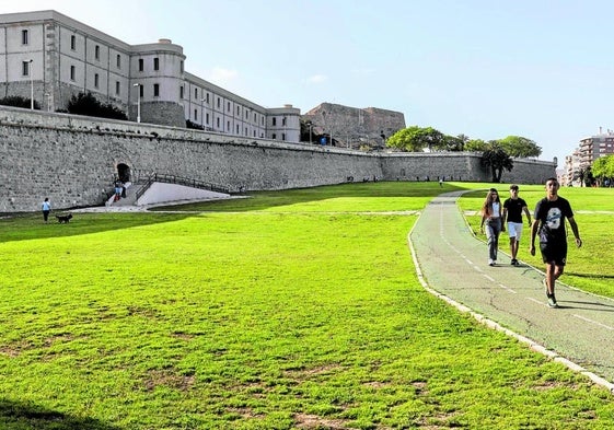 Varios jóvenes pasean por la Cuesta del Batel, con la Puerta del Socorro al fondo, cuya escalera de acceso deberá ser demolida.