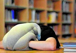 Un joven durmiendo en una biblioteca.