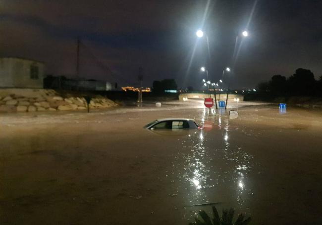 Un coche sumergido en la rotonda de entrada a Las Torres de Cotillas.