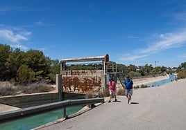 Dos personas pasean por la carretera del canal del postrasvase a su paso por la urbanización Villamartín, en Orihuela Costa.