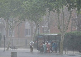 Varias personas se resguardan de la lluvia en Cartagena bajo una parada de bus.