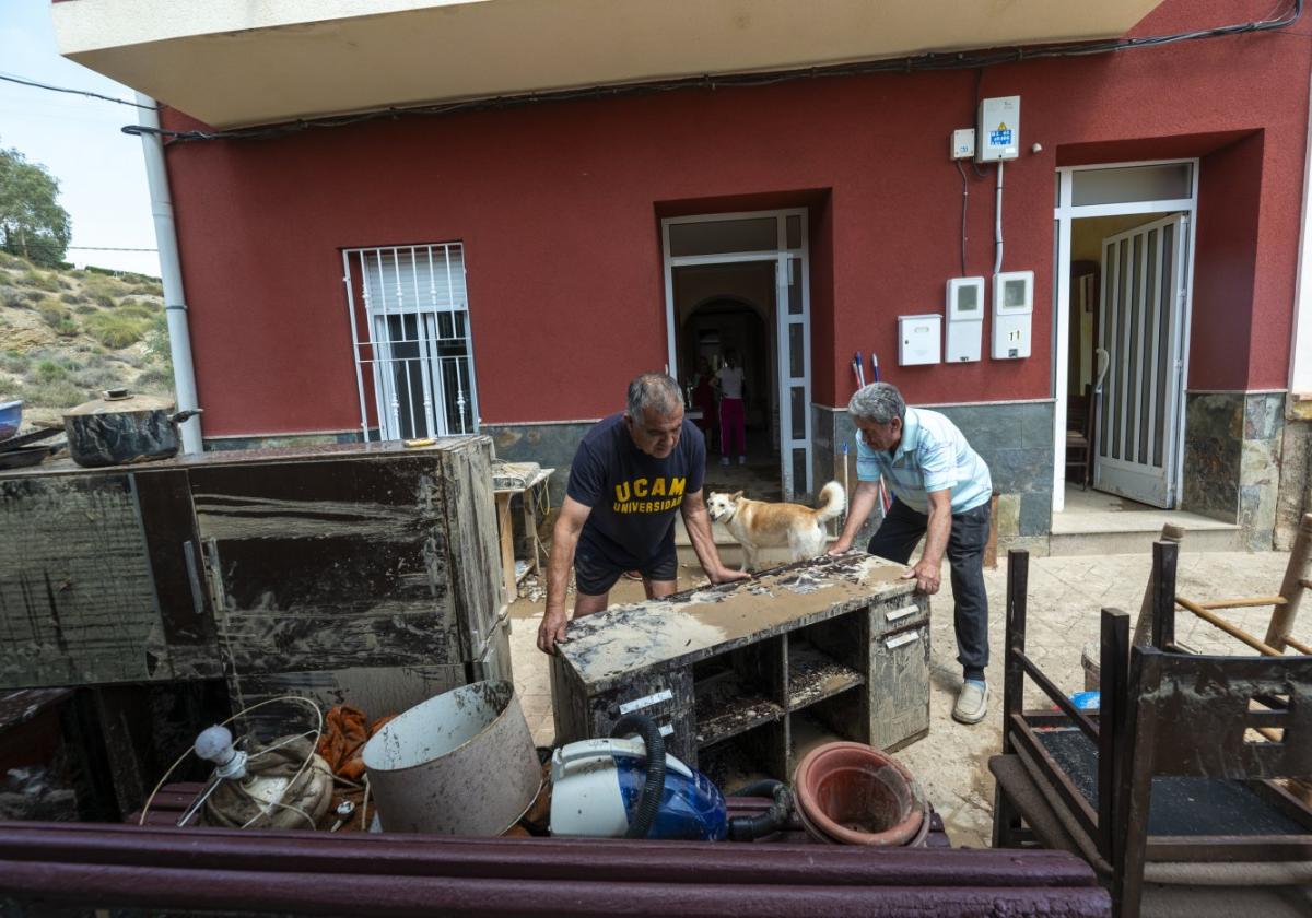 Francisco y su vecino sacan al exterior de la casa los muebles dañados, ayer, en Ribera de Molina.