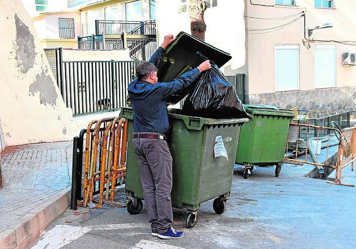 Un vecino deposita una bolsa de basura en un contenedor en una calle de Abarán, en imagen de archivo.