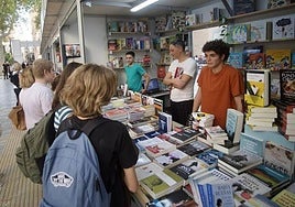 Varios jóvenes se acercan a un puesto en la Feria del Libro de Murcia.