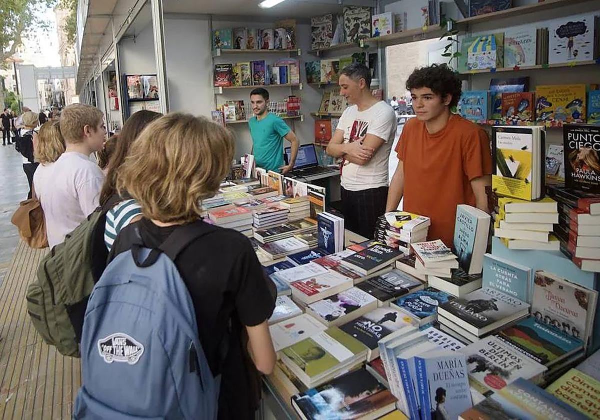Varios jóvenes se acercan a un puesto en la Feria del Libro de Murcia.
