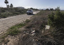 Un coche circula por un tramo de la Vía Verde del Campo de Cartagena, en cuyos arcenes se acumula basura y arbustos secos.