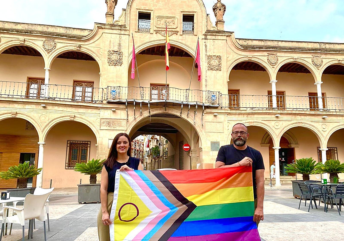 La concejala del PSOE sostiene la bandera LGTBI junto al presidente de la asociación Lorcaíris, Enrique Olcina, ante el Ayuntamiento.