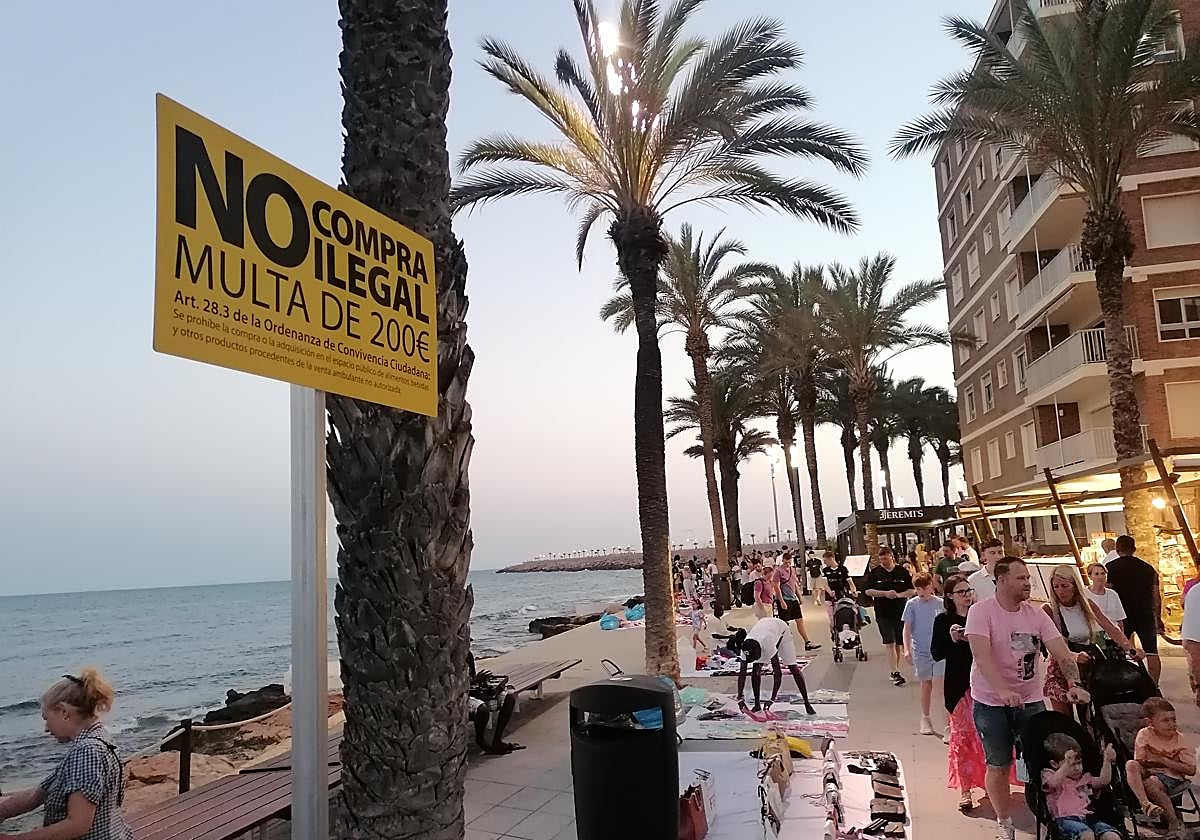 Los 'manteros' colocan sus productos a escasos metros del cartel que avisa de que la compra de los mismos está penada con multas de 200 euros.