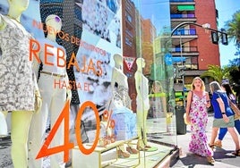 Reclamo comercial. Viandantes pasando por un escaparate del centro de Murcia que anunciaba rebajas de hasta el 40%.