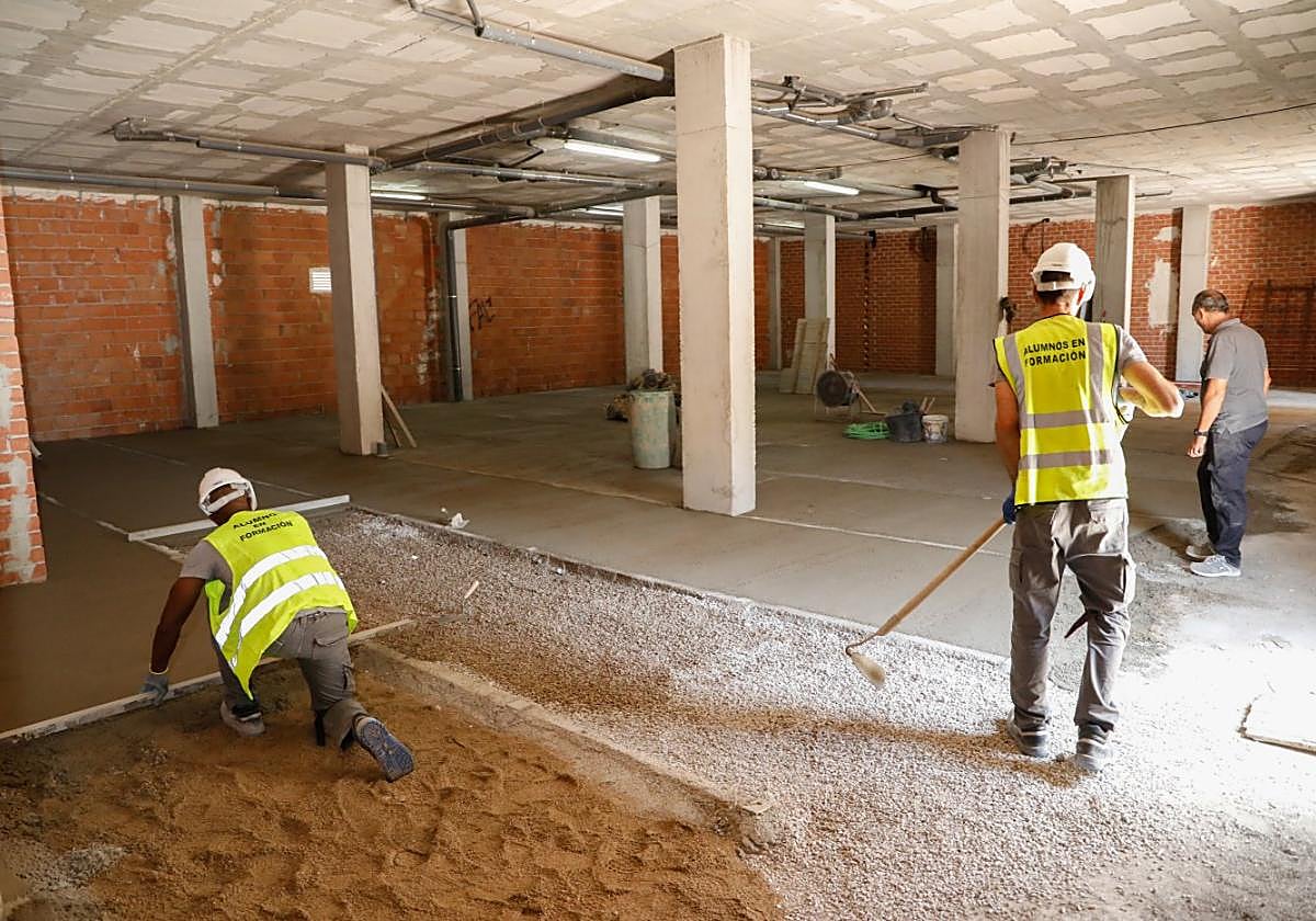 Alumnos del programa de empleo, supervisados por un monitor, trabajan en el local de la asociación, ayer.