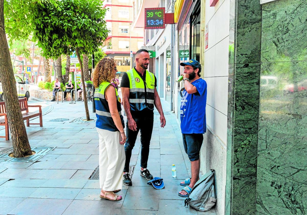 La trabajadora social María Martínez y el policía local Nicolás Hernández hablan con Fernando en la plaza Circular de Murcia.