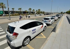 Fila de vehículos estacionados a pleno sol en el aeropuerto de Corvera, el pasado martes a mediodía, en la zona habilitada para taxis.