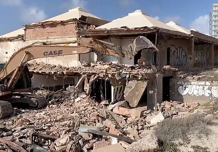 Una máquina derribando la galería comercial en ruina de La Manga.