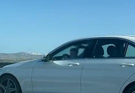 El menor sobre el regazo del conductor del vehículo.