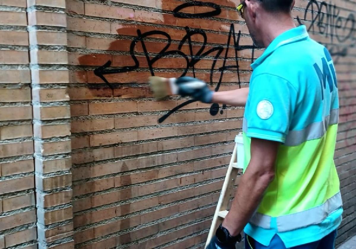 Un operario borra una pintada en una pared del centro de la ciudad.