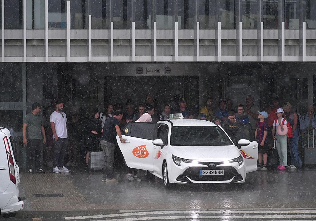 Imagen principal - Arriba: Un taxi se mete hasta la puerta de entrada del aeropuerto para recoger a un pasajero en plena granizada. Abajo izq.: El autobús directo al aeropuerto desde Murcia y Cartagena, con pocos viajeros de manera «habitual». Abajo der.: Varios pasajeros se dirigen a los controles de seguridad previos al acceso a la zona de embarques.