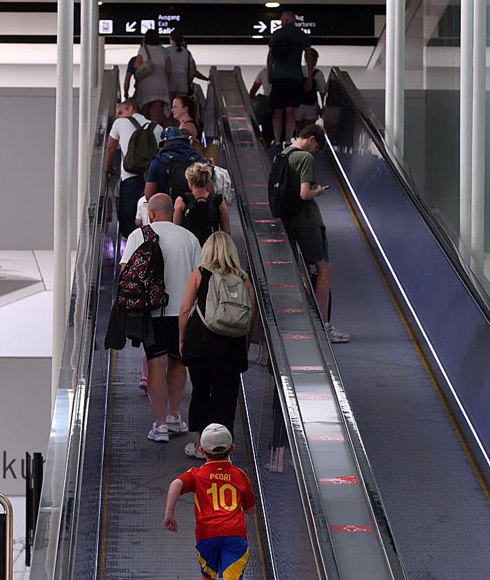Imagen secundaria 2 - Arriba: Un taxi se mete hasta la puerta de entrada del aeropuerto para recoger a un pasajero en plena granizada. Abajo izq.: El autobús directo al aeropuerto desde Murcia y Cartagena, con pocos viajeros de manera «habitual». Abajo der.: Varios pasajeros se dirigen a los controles de seguridad previos al acceso a la zona de embarques.