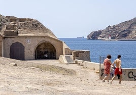 Dos personas, por la batería de San Leandro, deteriorada por el paso del tiempo.