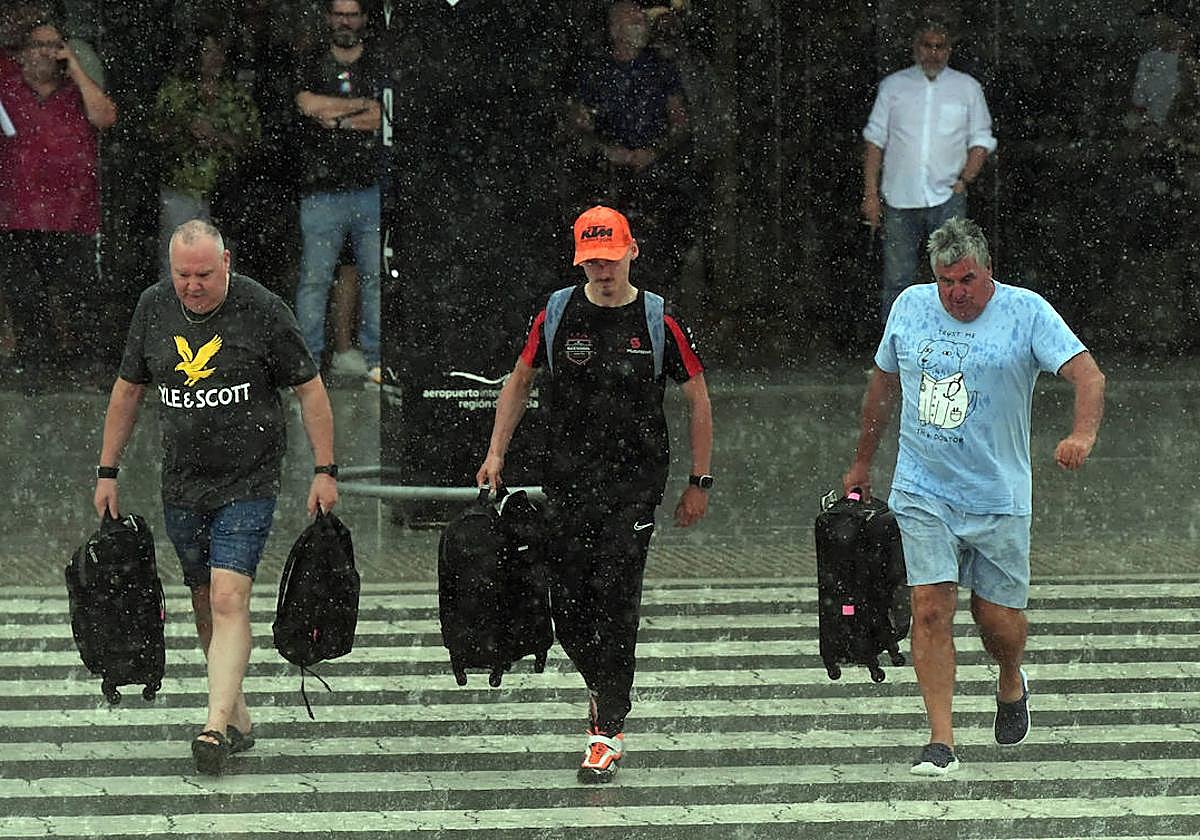 Tres personas cruzan un paso de cebra bajo un día de lluvia en Corvera, en una imagen de este mes de agosto.