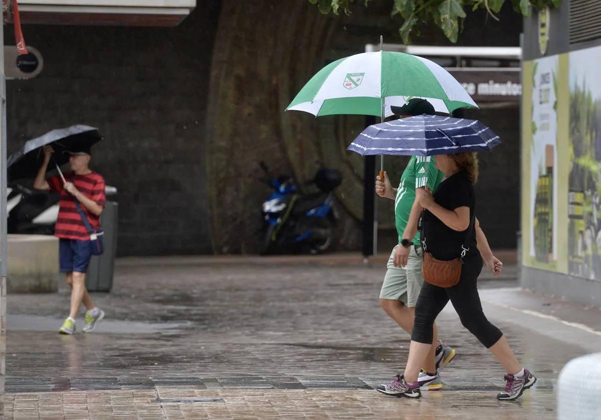 Tres personas pasean por Murcia con un paraguas para protegerse de la lluvia, en una imagen de archivo.