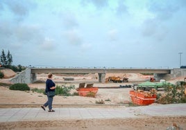 Una persona pasa junto a las obras del puente de la CV-95.